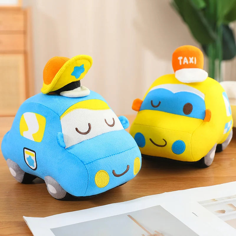 Two plush toy cars, one blue and one yellow with a taxi sign, on a wooden surface.