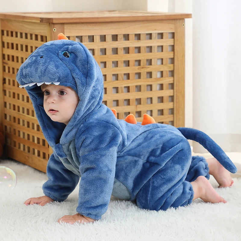 Child wearing a blue dinosaur onesie on a white carpet with a wooden cabinet in the background.
