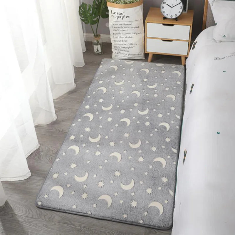 Grey rug with moon and star pattern on a wooden floor in a room.