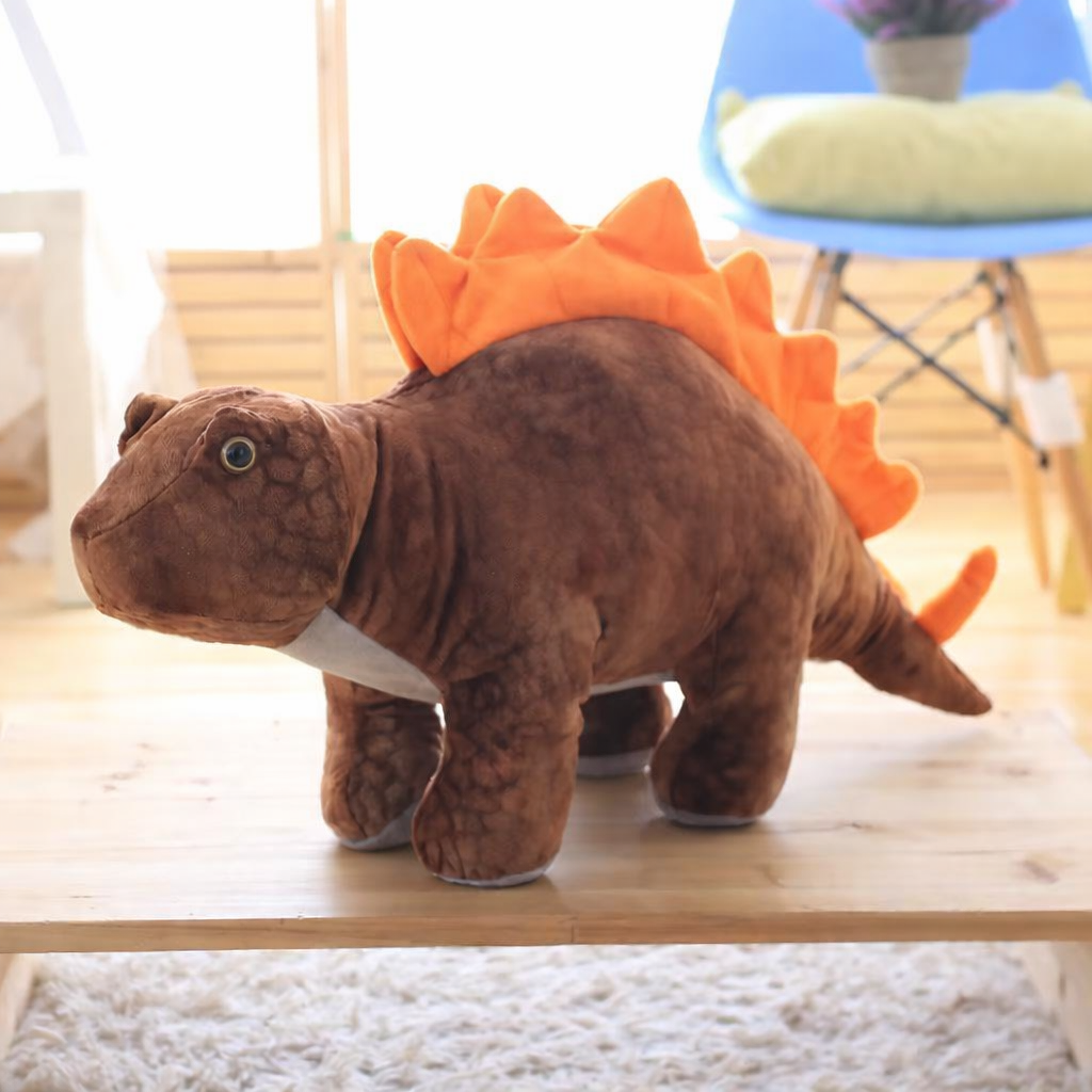 Brown soft plush stegosaurus dinosaur on a wooden surface in a living room setting.