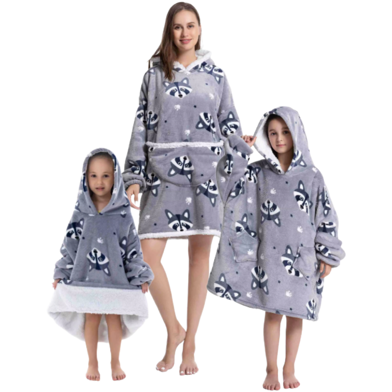 Adult and children wearing grey oversized wearable hoodies featuring a playful raccoon print and soft sherpa lining