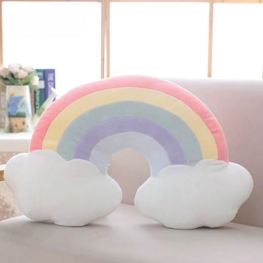 Pastel rainbow plush pillow with soft cloud details displayed on a sofa