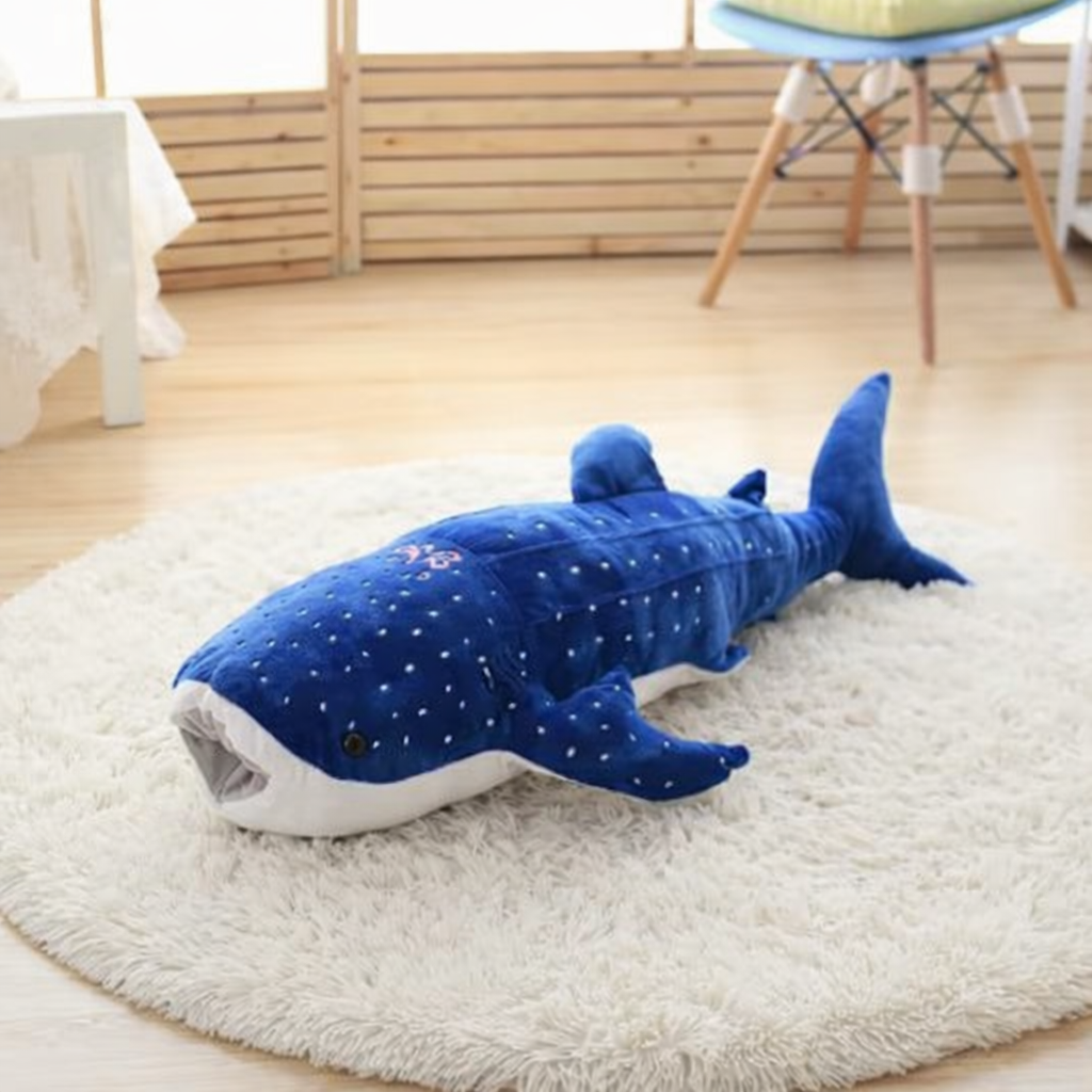 Blue soft plush whale toy lying on a white rug in a cosy room.