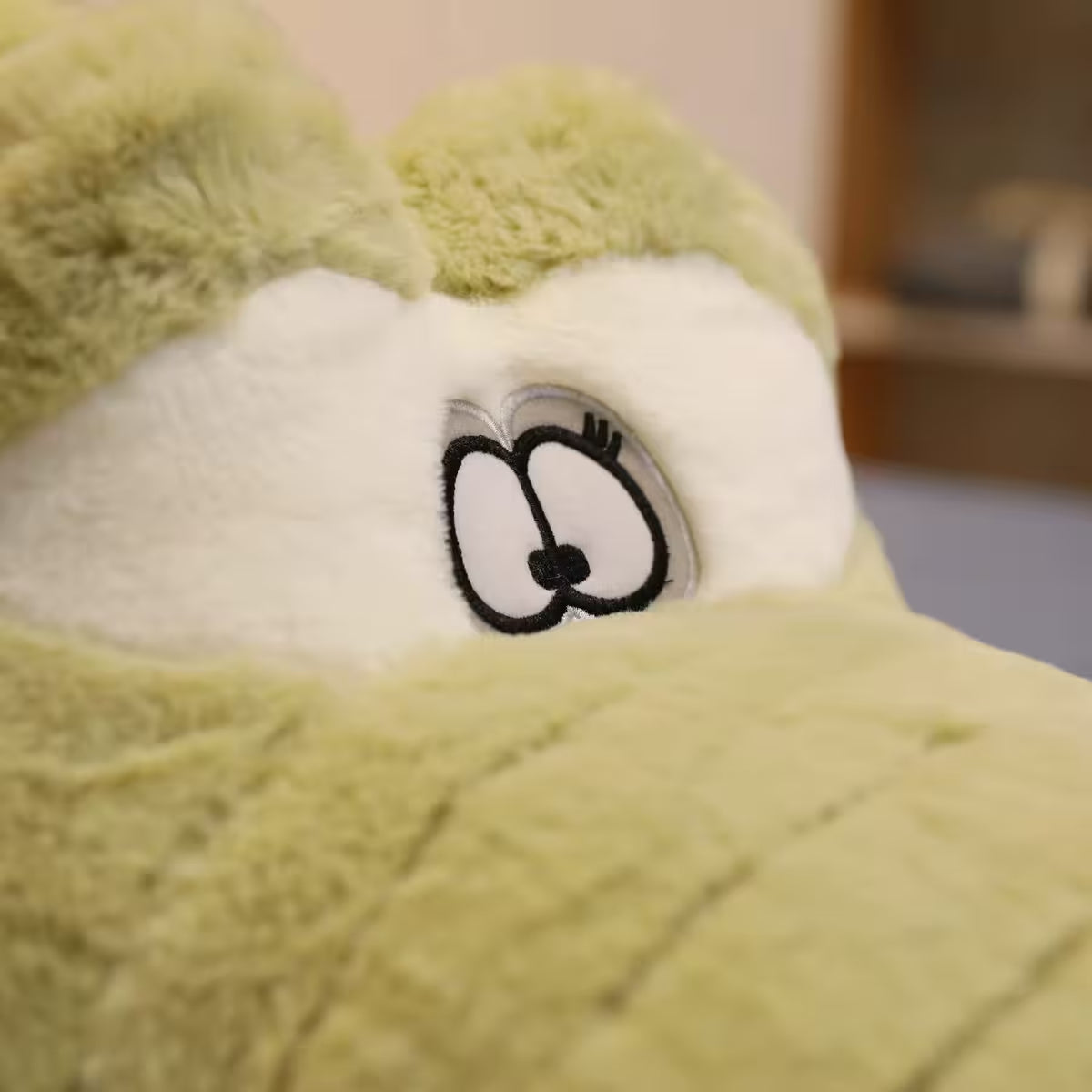 Close up of the eyes on a soft plush crocodile toy.