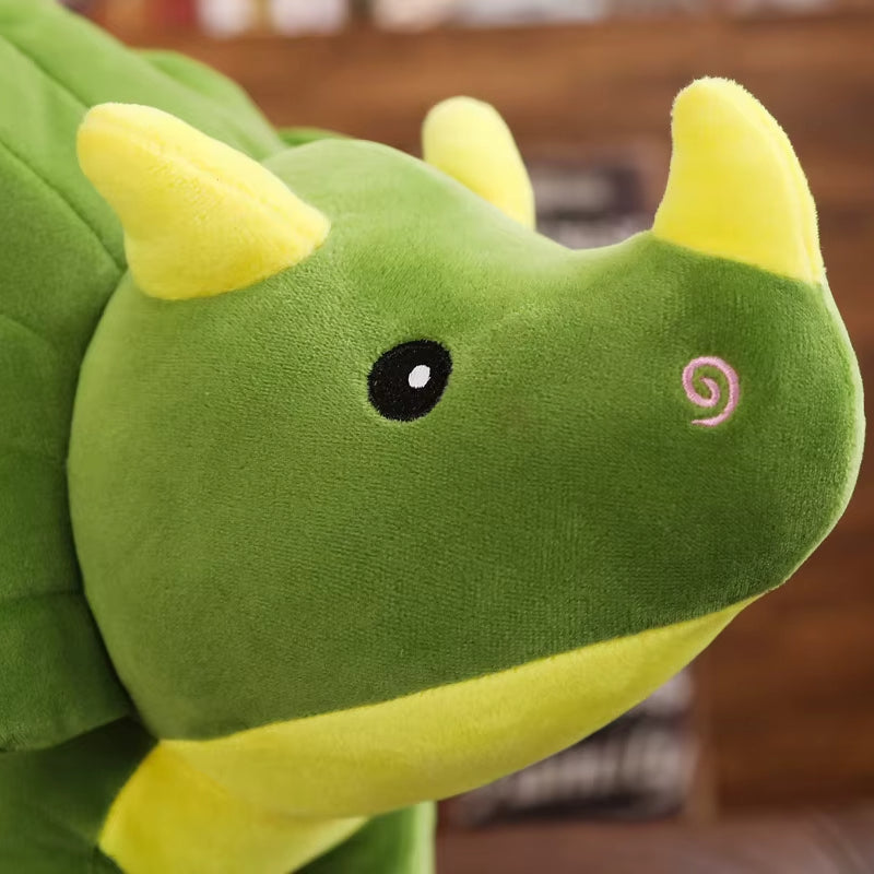 Close-up of a green plush triceratops toy with yellow horns on a blurred background
